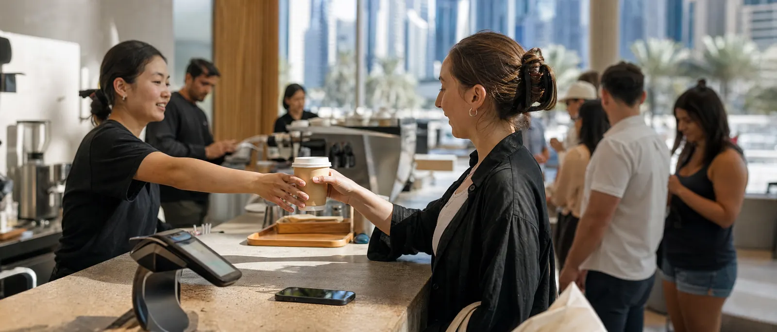 A café counter in Dubai with a phone lying beside the card reader